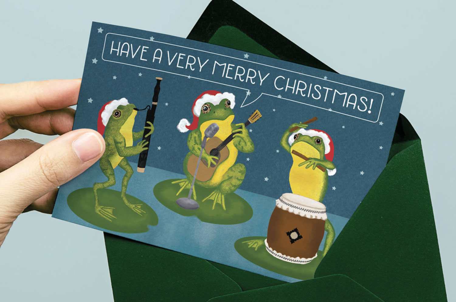 Christmas card featuring three frogs playing musical instruments